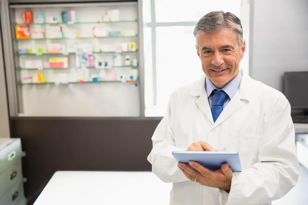 Foto de gestor de farmácia com tablet: calcular a margem de contribuição é fundamental